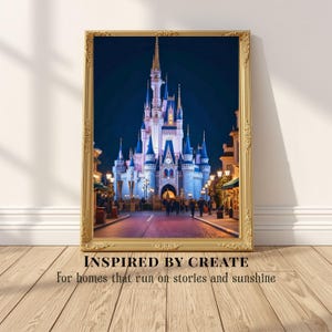 May include: A framed wall art print featuring a night view of a large, illuminated castle with blue spires and towers. The ornate gold frame surrounds the image. Below the frame, the text reads: INSPIRED BY CREATE For homes that run on stories and sunshine.