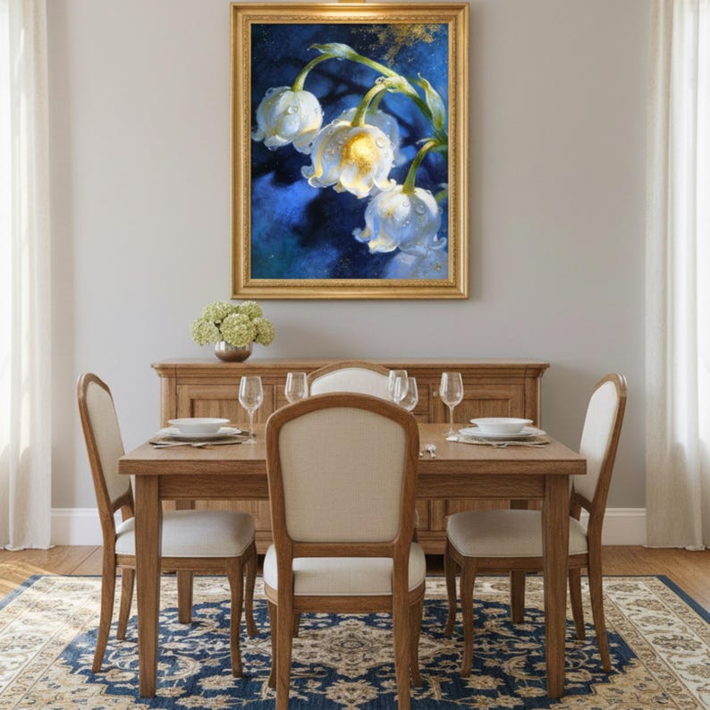 May include: A framed floral painting with a gold frame hangs above a wooden dining table set for a meal. The painting features white flowers with water droplets against a blue background. The dining set includes a wooden table, chairs, and a patterned rug.
