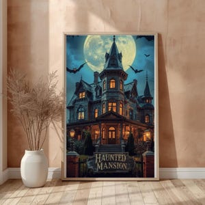 May include: A framed wall art print depicting a multi-story Victorian house at night under a large full moon. The house features glowing windows, a wrap-around porch, and a sign in the foreground that reads Haunted Mansion with bats.