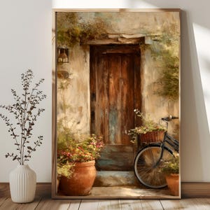 May include: A framed art print depicts a rustic scene with a weathered wooden door, a bicycle with a basket of flowers, and terracotta pots filled with plants. The artwork has a warm, inviting color palette with a focus on natural tones.