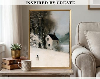 May include: A framed wall art print depicting a snowy winter landscape with a small white house, dark trees, and a snowman in the foreground. The scene features soft white snow, a dark chimney, and muted gray tones under a light sky.