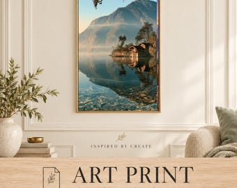 May include: A rectangular wall art print featuring a landscape of a mountain reflecting in a calm lake with a small wooden cabin on the shore. The scene includes soft morning light, clear water, and trees. The text reads INSPIRED BY CREATE ART PRINT.