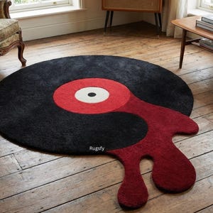 May include: A circular black rug with a red and white centre, designed to look like a vinyl record. A red, abstract shape extends from the record's edge. The rug is on a wooden floor.