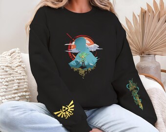 May include: Black sweatshirt featuring a silhouette design with a figure holding a sword, set against a sunset backdrop. The sleeves have gold and teal graphics. A gold emblem is on the left sleeve.
