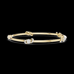 May include: A gold bangle bracelet with three diamond-studded decorative elements. The bracelet has a simple, elegant design with a polished finish. The diamonds are set in a pave style, adding sparkle and sophistication to the jewelry.