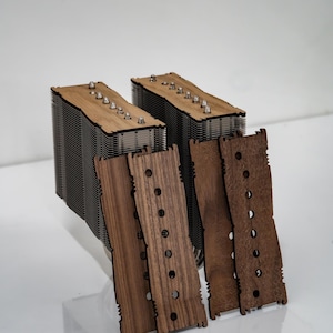 May include: Two computer CPU coolers with wooden tops and metal fins. Four wooden panels with holes are in front of the coolers. The coolers have silver screws on top. The wood is light brown and the metal is silver.