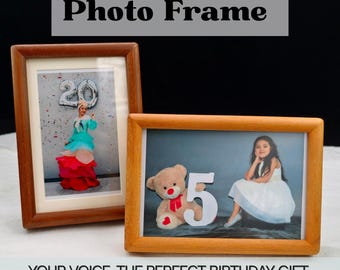 Pode incluir: Duas molduras de fotos de madeira. Uma moldura exibe uma foto de uma pessoa com um vestido colorido e um grande balão prateado. A outra moldura mostra uma menina em um vestido branco com um ursinho de pelúcia e o número 5. O texto no topo diz "Custom Voice Photo Frame."