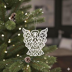 Może przedstawiać: Biała, misternie zaprojektowana ozdoba choinkowa w kształcie anioła wisząca na zielonej choince. Anioł ma szczegółowe skrzydła i aureolę. Drzewko jest ozdobione małymi białymi światełkami i szyszkami.