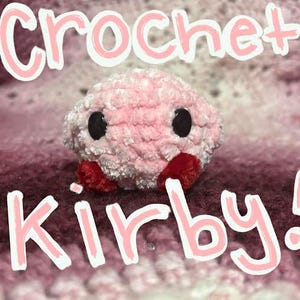Puede incluir: Un peluche Kirby rosa hecho a mano con ganchillo, con ojos negros y pies rojos. La palabra "Crochet" está escrita encima del peluche, y la palabra "Kirby!" debajo, ambas en letras rosas y blancas.