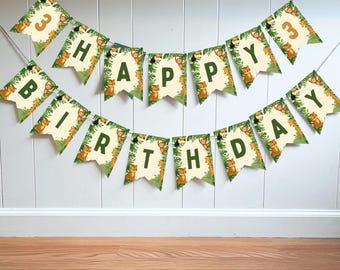 May include: A festive banner with the words "HAPPY BIRTHDAY" and the number "3" displayed on individual pennants. Each pennant features a jungle theme with tigers, monkeys, and toucans, surrounded by green foliage. The banner is strung against a white wall.
