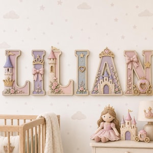 Könnte beinhalten: Ein Set aus dekorativen Wandbuchstaben, die LILIAN in einer pastellfarbenen Palette aus Rosa, Lila und Creme buchstabieren. Jeder Buchstabe zeigt komplexe 3D-Details wie Miniaturschlösser, Kronen, Schleifen, Sterne, Herzen und florale Akzente.