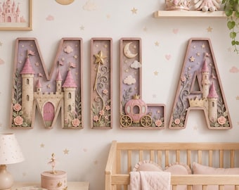 May include: Four large, decorative wooden letters spelling MILA, each featuring intricate 3D relief designs. The letters include sculpted castles, a magic wand, a carriage, and floral accents in shades of soft pink, cream, and lavender.