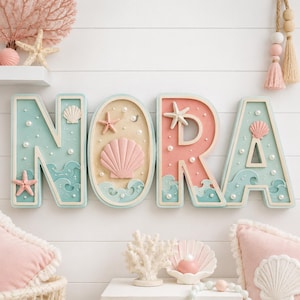 Puede incluir: Un letrero decorativo de pared que deletrea el nombre NORA en letras grandes y tridimensionales. Cada letra presenta un tema costero con colores azul y rosa pastel, adornado con estrellas de mar en miniatura, conchas y perlas blancas.