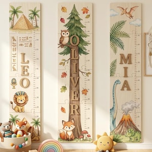 May include: Three wooden growth charts with painted illustrations and names. One features a pyramid, palm trees, and the name "LEO". Another has a tree, owl, fox, and the name "OLIVER". The third shows dinosaurs and the name "MIA". Each chart has inch markings.
