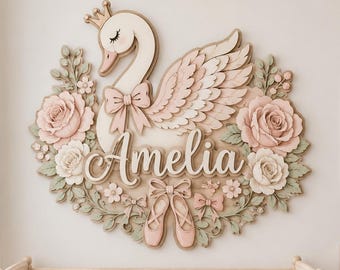 May include: A wall-mounted wooden sign featuring a swan wearing a crown, surrounded by pink and white roses, green leaves, and ballet slippers. The name Amelia is written in white cursive script in the center, accented by small bows.