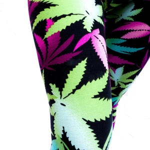 May include: Leggings with a vibrant pattern of cannabis leaves. The leaves are in shades of neon green, pink, and teal against a black background. The fabric appears to be stretchy and form-fitting.