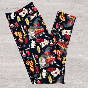 May include: Black leggings with a repeating pattern of wizarding school imagery. The design includes a wizard's hat, a cage, a scarf, keys, feathers, potion bottles, and letters. The leggings are made of a soft, stretchy material.