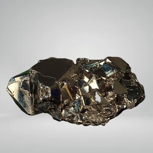 Op de afbeelding: Een cluster van pyrietkristallen, ook wel bekend als 'fool's gold', met een metalen, reflecterend oppervlak. De kristallen hebben een donkere, messingkleur met een complexe, geometrische structuur. Het mineraalmonster wordt tegen een neutrale achtergrond getoond.