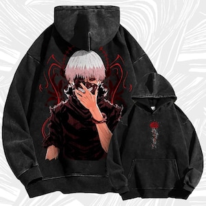 Puede incluir: Dos sudaderas con capucha negras. La sudadera más grande presenta un gráfico de un personaje con cabello blanco y una máscara, con detalles en rojo. La más pequeña tiene un diseño floral rojo. Ambas tienen un aspecto vintage desgastado.