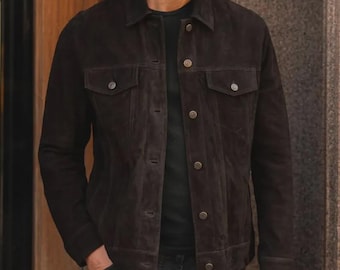 Könnte beinhalten: Dunkelbraune Wildlederjacke mit klassischem Design. Die Jacke hat eine Knopfleiste, zwei Brusttaschen und geknöpfte Manschetten. Die Jacke ist mittelschwer und hat einen Kragen.