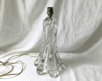May include: A clear glass table lamp with a swirling design. The lamp has a silver metal base and a clear cord.