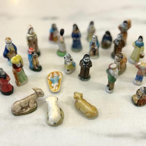 Puede incluir: Una colección de pequeñas figuras de cerámica pintadas a mano que representan una escena de la Natividad. Las figuras incluyen a María, José, el niño Jesús, ángeles y animales. Las figuras son de varios colores y estilos.