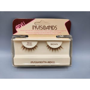 May include: A package of Ardell Invisibands Demi Pixies false eyelashes in brown. The packaging includes the brand name, product name, and a description of the product. The lashes are displayed in a clear plastic case.