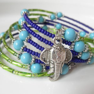 May include: A multi-strand bracelet with green, blue, and silver beads. The bracelet features a silver elephant charm.