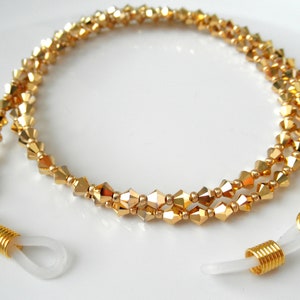 May include: Gold-tone beaded eyeglass chain with clear plastic end pieces. The chain is made of small, faceted beads.