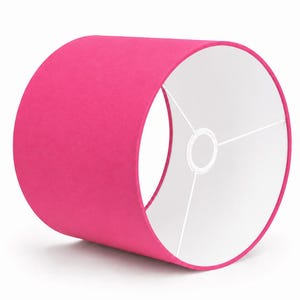 Peut inclure: Un abat-jour cylindrique doté d'un tissu extérieur rose vif. L'intérieur de l'abat-jour est doublé d'un matériau blanc uni. Une armature métallique blanche à trois branches est centrée à l'intérieur pour soutenir l'ampoule de la lampe.