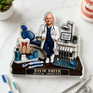 May include: A custom acrylic desk display featuring a dental assistant figure holding a tooth model, standing next to a dental chair, equipment, and tools. The base is dark wood with a gold plaque reading DAVID SMITH - DENTAL ASSISTANT -.
