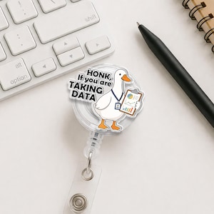 Peut inclure: Un badge reel blanc avec un dessin d'oie tenant un presse-papiers avec des graphiques. Le badge reel porte le texte "HONK, If you are TAKING DATA". L'oie a un bec et des pattes oranges, et un cordon bleu.