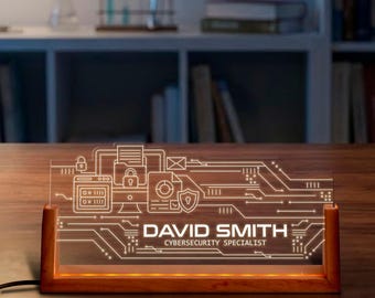 May include: A lit desk nameplate with a circuit board design. The nameplate is made of clear acrylic and sits in a wooden base. The name "DAVID SMITH" and title "CYBERSECURITY SPECIALIST" are displayed in white.
