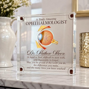 May include: A square clear acrylic plaque featuring a colorful anatomical illustration of a human eye. The text reads: A Truly Amazing OPHTHALMOLOGIST, Dr. Mathew Moore, Is hard to find, difficult to part with, and impossible to forget.