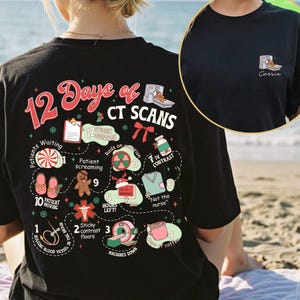 May include: Black t-shirt with a colorful graphic design. The design features the text "12 Days of CT Scans" with various medical-themed illustrations and text. A smaller image of a CT scanner is on the front, with the name "Carrie" below it.