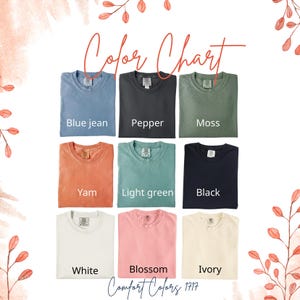 Puede incluir: Una carta de colores con nueve camisetas Comfort Colors 1717 en varios tonos. Los colores incluyen azul vaquero, pimienta, musgo, &ntilde;ame, verde claro, negro, blanco, flor y marfil. Las palabras "Color Chart" y "Comfort Colors 1717" est&aacute;n escritas en cursiva.
