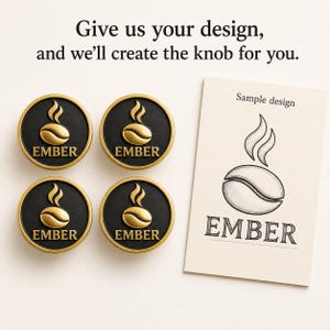 May include: Four circular cabinet knobs with a black centre and gold rim, each featuring a gold coffee bean icon and the text EMBER. A rectangular card displays the text Sample design and a line drawing of the coffee bean logo and the word EMBER.