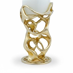 May include: A gold-colored, abstract candle holder with a white candle. The holder has an open, organic design with a circular base. The candle is a square shape.