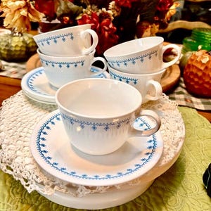 May include: A set of three ceramic mugs with a speckled, matte finish. The mugs are in shades of cream, light brown, and dark brown. Each mug has a simple, minimalist design and a rounded handle.