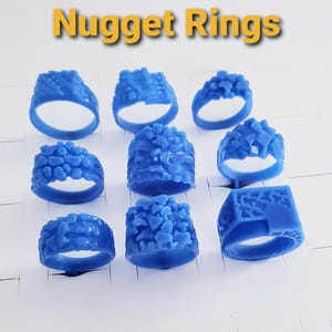May include: A collection of eight blue wax nugget rings arranged in a grid. Each ring features a distinct textured surface with irregular, raised shapes resembling natural nuggets. The text Nugget Rings is displayed in yellow at the top of the image.