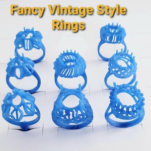 May include: Eight blue wax ring models for jewelry casting, arranged in a grid. Each ring features a unique, intricate openwork setting design. The text "Fancy Vintage Style Rings" is displayed in yellow at the top of the image.