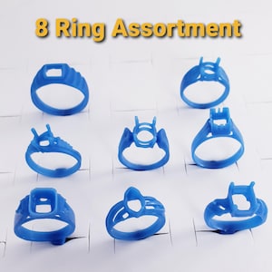 May include: An assortment of eight blue wax ring models for jewelry casting, each featuring a unique setting style. The text 8 Ring Assortment is displayed at the top. These items are designed for lost-wax casting processes to create custom jewelry pieces.