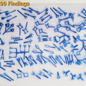 May include: A collection of 200 blue wax jewelry findings for casting, featuring various prong settings, ring mounts, and intricate connector shapes arranged on a white surface. These wax models are used for jewelry making.