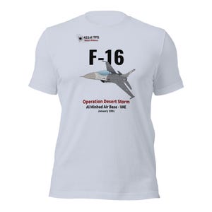 May include: White t-shirt with a graphic of an F-16 fighter jet. The text includes "F-16", "Operation Desert Storm", and "Al Minhad Air Base - VAE, January 1991". The shirt also has the text "421st TFS Black Widows".