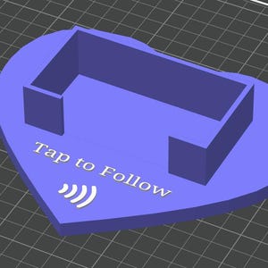 Può includere: Oggetto a forma di cuore viola stampato in 3D con una struttura rettangolare e la scritta "Tap to Follow" con un simbolo Wi-Fi. L'oggetto è probabilmente un elemento decorativo o funzionale.