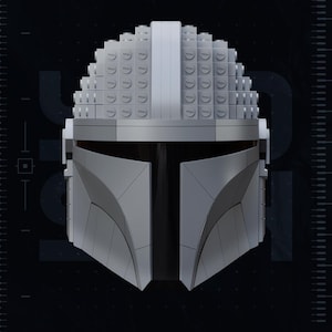 May include: A gray Mandalorian helmet constructed from interlocking blocks, with a dark visor. The helmet's design is angular and geometric, with a textured surface. The image includes the text "TEST PRINTED AMS COLORED STL" and "PATREON.COM/YOSHSTUDIOS".