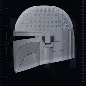 May include: A gray Mandalorian helmet constructed from interlocking blocks, with a visor and a rounded top. The image includes the text "TEST PRINTED AMS COLORED STL" and "PATREON.COM/YOSHSTUDIOS".