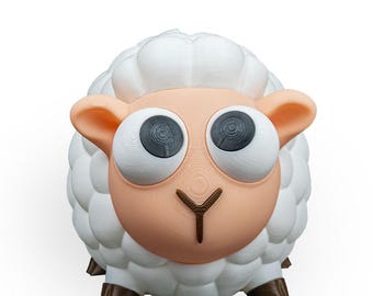 May include: A whimsical, 3D-printed sheep figurine. The sheep features a fluffy white body, large black and white eyes, and a light brown face and ears. The figurine has a cartoonish design, with a brown 'Y' shaped nose.