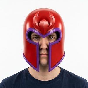May include: A red and purple helmet featuring a smooth, rounded dome with a prominent central crest and a wide, angular face opening. The design includes a distinct purple trim outlining the eye and nose area, creating a bold, structured appearance.