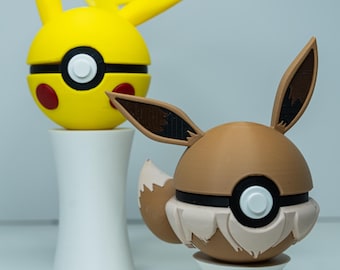 May include: Two 3D-printed figures of Pokémon characters Pikachu and Eevee. Pikachu is yellow with black-tipped ears and red cheek circles. Eevee is brown with a fluffy tail and ears. Both are on white pedestals.